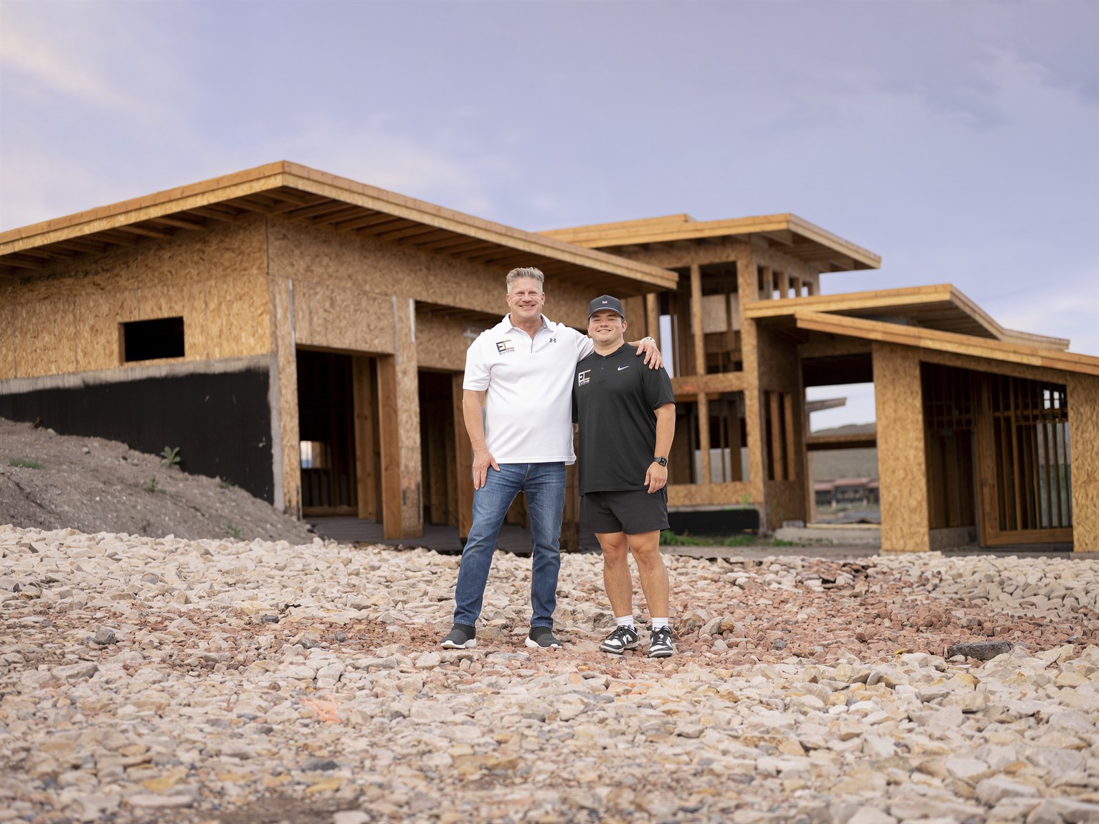 Austin and Paul Ewing standing together at a custom home under construction